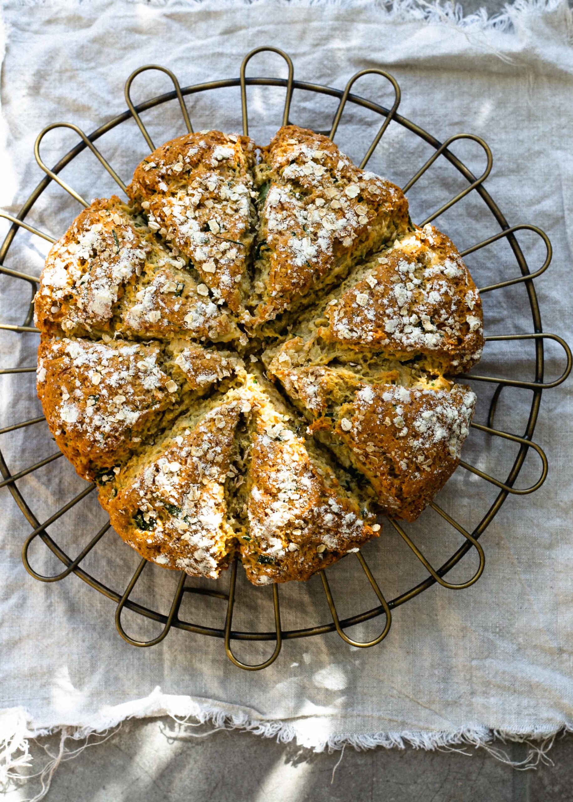 Gluten-free cheddar cheese and spring onion soda bread on a cooling rack with oat topping