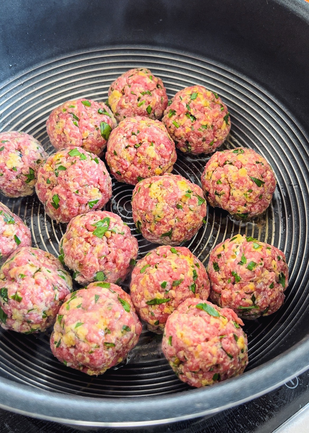 Juicy gluten free meatballs cooking in a pan with herbs
