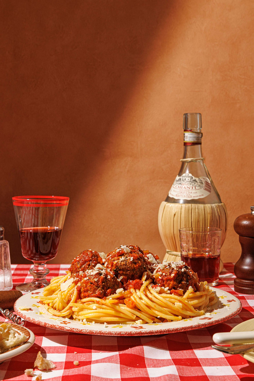 Side on view of juicy gluten free spaghetti and meatballs on a table with red wine